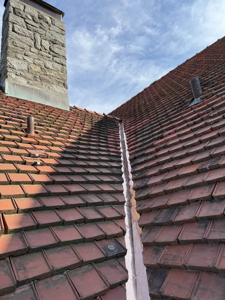 Finished copper valley flashing beside a stone chimney